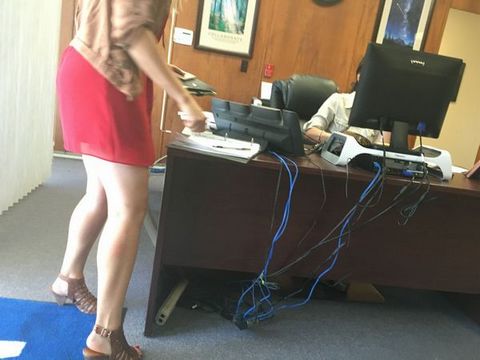 Модель со свелыми волосами в офисе в короткой юбочке